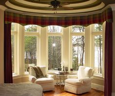 a living room filled with white furniture and large windows covered in plaid drapes