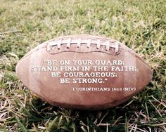 an old football laying in the grass with a bible verse on it's side