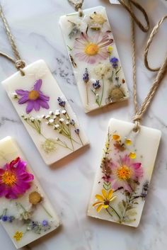 four flower pendants are shown on a marble surface