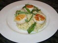 a white plate topped with rice and scallops on top of a countertop