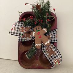 a gingerbread man cookie tray with christmas decorations and greenery on it, hanging from a wall