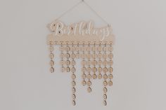 a wooden birthday sign hanging on a wall with beads and chains attached to it's side