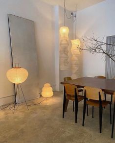 a dining room table and chairs with lights on the wall behind them in front of a mirror