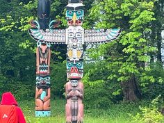 two totems are standing in the grass near trees