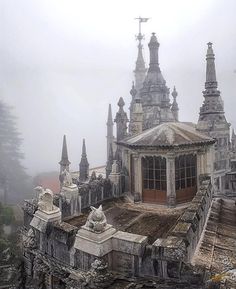 an old building with many spires and windows in the middle of it on a foggy day