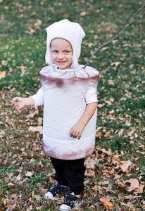 a young child in a costume standing on leaves