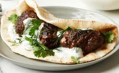 meatballs in pita bread with sour cream and cilantro on the side