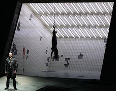 a man standing in the middle of a room with two people hanging upside down from the ceiling