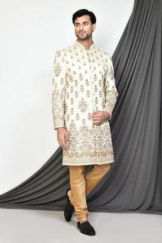 Ivory sherwani with all-over floral embroidery. Comes with dark beige churidar.
Components: 2
Pattern: Embroidered
Type Of Work: Floral
Neckline: Mandarin
Sleeve Type: Full
Fabric: Sherwani: Mulberry, Churidar: Dupion Silk,
Color: Ivory
Other Details: 
Embroidered shank buttons
Closure:
Sherwani: Front buttons
Churidar: Front drawstring
Occasion: Wedding,Groom - Aza Fashions Gold Sherwani, Ivory Sherwani, Embellished Buttons, Sherwani For Men, Zari Embroidery, Couture Jackets, Nehru Jackets, Dupion Silk, Dark Beige