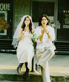 two people are sitting on a bench eating ice cream and drinking soda while the woman is holding a flower in her hand