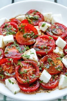 a white plate topped with sliced tomatoes and feta cheese