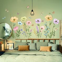 a bed room with a neatly made bed and flowers painted on the wall