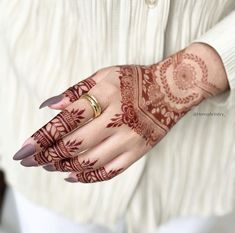 a woman's hand with henna tattoos on her left arm and right hand