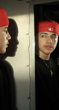 two young men standing next to each other in front of a mirror with their shadows on the wall