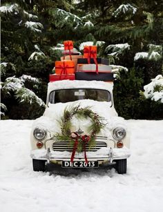 an old car covered in snow with presents on the roof and wreaths on top