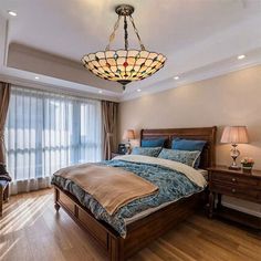 a bedroom with a large bed and wooden flooring, along with two lamps on either side of the bed