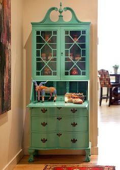 a green china cabinet sitting in the corner of a room