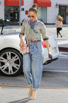 a woman walking down the street carrying a pink purse