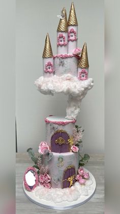 a three tiered cake decorated with pink and gold princess castle decorations on top of it