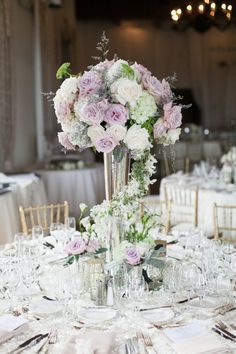 a tall vase filled with pink and white flowers on top of a dining room table