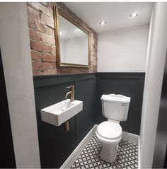 a white toilet sitting next to a sink in a bathroom under a mirror on the wall