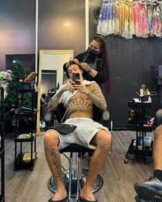 a man getting his hair cut at a barbershop while another person looks on