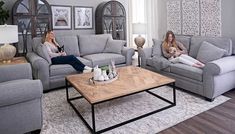 two women sitting on couches in a living room with coffee table and rugs