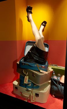 a woman laying on top of luggage with her legs up in the air and wearing high heels