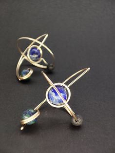 These elegant and futuristic earrings are an original design. Inspired by earths gravitational tidal lock and the three body problem. Three astral bodies in each others orbit.   Enjoy the deep vibrant colors of these gemstones against yellow gold.  These lightweight earrings are made to the golden ratio, considering proportion and negative space. Featuring a Lapis Lazuli gemstone planet, a black lava stone moon and an Azurite satellite planet. Gemstones are carefully selected for their aesthetic Modernist Nickel Free Earrings As Gift, Nickel Free Modernist Earrings For Gift, Golden Ratio Design, Spiritual Blue Brass Jewelry, Modernist Metal Earrings As Gift, Modernist Pierced Jewelry For Gift, Modernist Metal Jewelry, Futuristic Earrings, Spiritual Blue Gold-plated Jewelry