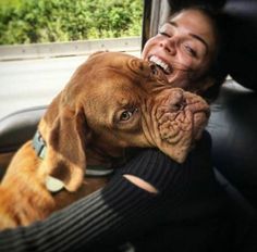 a woman sitting in the back seat of a car with a dog on her lap