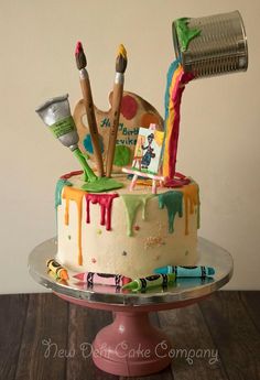 there is a cake that has been decorated with paint and brushes on the top layer