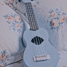 a ukulele sitting on a bed with floral sheets