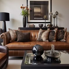 a living room filled with lots of brown furniture and pillows on top of leather couches