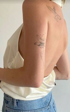 the back of a woman's shoulder with tattoos on her left arm and right arm