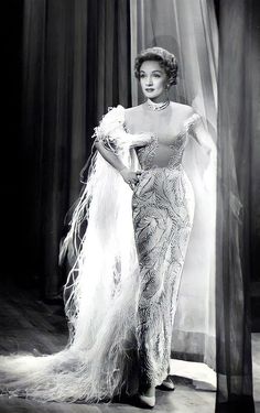 an old black and white photo of a woman in a feathered dress