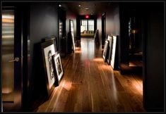 an empty hallway with framed pictures on the wall and wooden floors in front of it