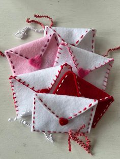 several small envelopes made out of felt with red and white stitching on them