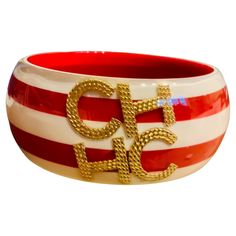 This is a Carolina Herrera red and white resin bangle. It depicts a red and white "peppermint starlights” pattern. It is adorned in the center with gold tone double upper case initials of CH from Carolina Herrera. Red Bangle Fine Jewelry, Red Fine Jewelry Bangle, Unique Red Bangle Jewelry, Carolina Herrera Jewelry Accessories, Red Enamel Bangle, Red Hand-strung Bangle Bracelet, Bruce Weber, Diana Vreeland, Resin Bangles