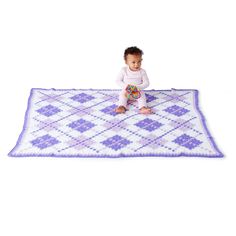 a baby sitting on top of a purple and white rug