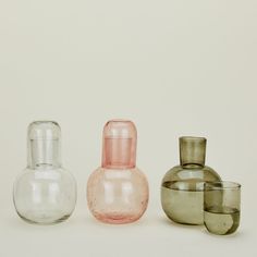 three different colored glass vases sitting next to each other