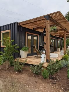 a house made out of shipping containers with a covered porch and patio area next to it