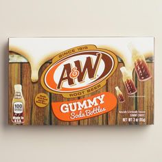 a box of gummy soda bottles sitting on top of a wooden table next to an orange and white sign