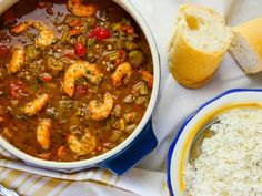 a bowl of shrimp and rice next to a loaf of bread on a white towel