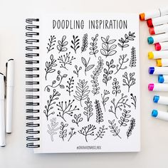 a notebook with doodling instructions and markers next to it on a white surface surrounded by crayons