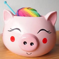 a pink piggy bank with yarn in it's eyes