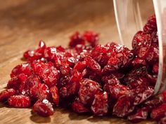 a plastic container filled with cranberries sitting on top of a wooden table next to a knife