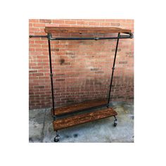 a wooden shelf sitting on wheels in front of a brick wall with an iron bar