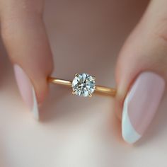 a woman's hand holding a gold ring with a diamond on the top and bottom