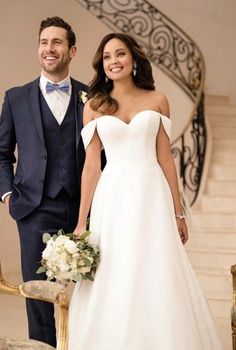 a man and woman in formal wear standing next to each other on the stairs at their wedding