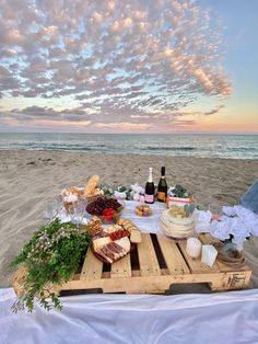 a picnic on the beach with food and drinks laid out in front of the ocean